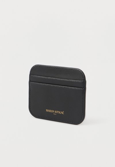 Μαύρη δερμάτινη θήκη καρτών με απαλή υφή, που διαθέτει δύο εξωτερικές θήκες και χρυσές λεπτομέρειες branding. Συμπαγές ορθογώνιο σχήμα.