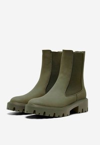 Bottines vertes avec panneaux latéraux en élastique, semelle en caoutchouc et finition texturée. Semelle épaisse et crantée pour une meilleure adhérence et durabilité.
