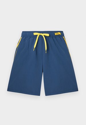 Blauwe korte broek met gele trekkoord, zijstrepen en "Moschino" logo op de tailleband, plat gelegd op een lichte achtergrond.