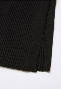 Tessuto a maglia nero a coste con una texture liscia, caratterizzato da uno spacco laterale all'orlo e da un motivo verticale su tutta la superficie.
