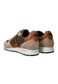 Bruine en beige suède sneakers met leren accenten, witte zool en zwarte rubberen buitenzool. Beschikt over branding op de hiel en zijkant.