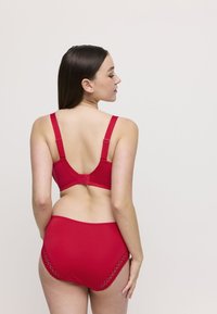 Reggiseno rosso e slip alto abbinato, realizzati in tessuto liscia, con spalline regolabili e bordi decorati da pizzo.