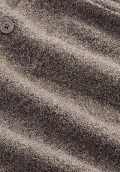 Tissu en feutre de couleur marron atténuée, présentant une surface texturée avec des fibres visibles et un détail unique d'un bouton.