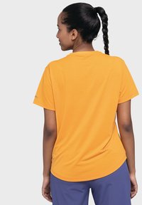 Short-sleeve orange T-shirt with a round neckline, smooth texture, and slightly curved hem. Features logo detail on the left sleeve.