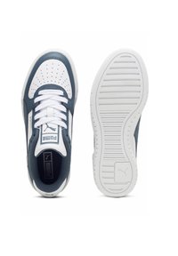 Baskets Puma présentant une tige en cuir blanc avec des accents marine, une pointe perforée, des lacets blancs et une semelle extérieure texturée blanche.