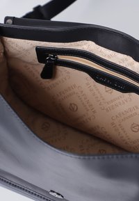 Sac à main en simili cuir gris avec un extérieur lisse, doté d'un intérieur à motif beige et d'une poche zippée avec bord noir.
