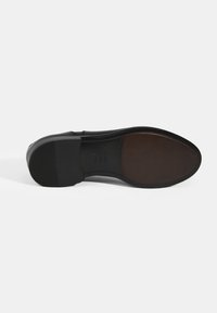 Semelle de chaussure en cuir noir avec une finition lisse et polie. Dotée d'un bout arrondi et d'une traction en caoutchouc au talon pour plus d'adhérence. Accent marron au niveau du fond.