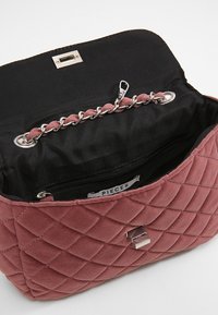 Borsa in velluto rosa polveroso trapuntata con tracolla in catena argentata, fodera interna nera, tasca con zip e chiusura magnetica argentata.