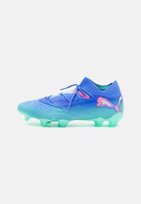Blue and green soccer cleat with a textured mesh upper, rounded toe, and translucent outsole. Features pink accents and a knitted collar.