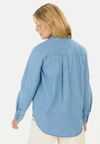 Lichtblauwe spijkerblouse met knopen, met lange mouwen, een achterplooi en een ronde zoom, voorzien van knopenmanchetten en een losse pasvorm.