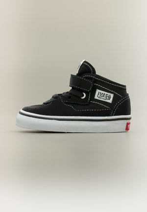 Basket montante noir et blanc pour tout-petit avec fermeture Velcro, lacets, écusson '"Half Cab"' et semelle en caoutchouc blanc à bout texturé.