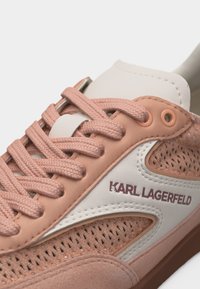 Κοντινό πλάνο ροζ και λευκού αθλητικού παπουτσιού Karl Lagerfeld με υφασμάτινα κορδόνια, διάτρητες πλευρικές επιφάνειες και λογότυπο στη πλευρά.