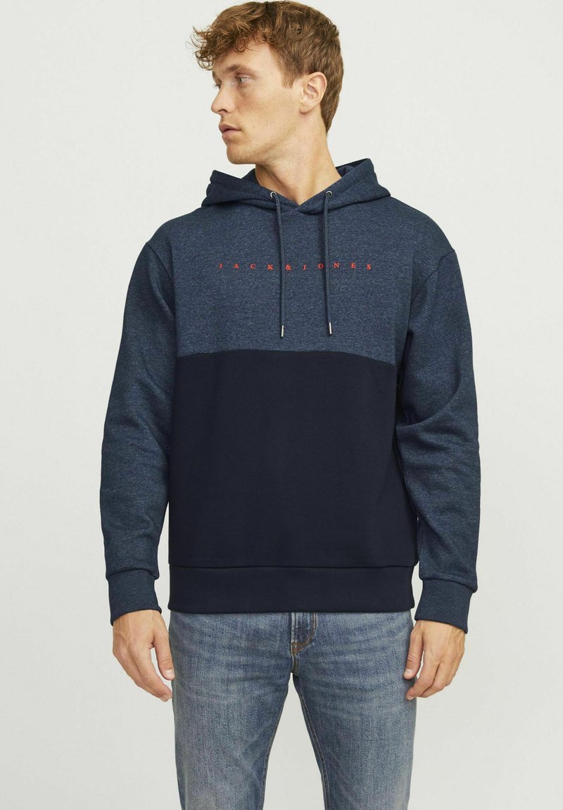 Sudadera con capucha en navy y azul oscuro. Cuenta con un bolsillo frontal, capucha con cordón y texto de logo en rojo que contrasta en el pecho.
