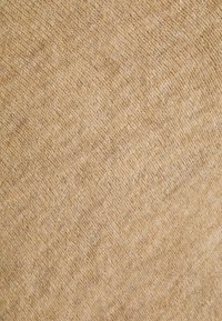 Tkany materiał o lekkim beżowym kolorze, charakteryzujący się miękkim, plecionym wyglądem z delikatnymi ukośnymi liniami i subtelnymi różnicami w odcieniu.