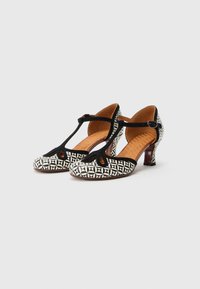 Ασπρόμαυρα παπούτσια με τακούνι και σχέδιο T-λαιμού, με στρογγυλεμένη μύτη. Διαθέτουν υφασμένη εσωτερική σόλα και μικρό τετράγωνο τακούνι.