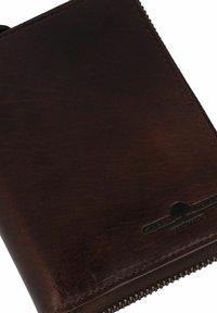 Billetera de cuero marrón con textura suave, cierre de cremallera y detalle de logo grabado. Presenta esquinas redondeadas y costuras visibles.