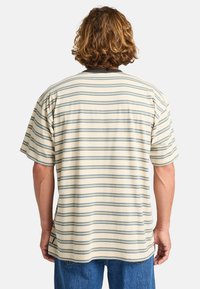 Short-sleeve, crew-neck shirt in cream with blue and green horizontal stripes; soft cotton texture; side slit details at the hem.