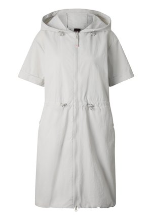 Woman wearing a light gray hooded knee-length dress with front zipper, short sleeves, pockets, white sneakers, and a backward white baseball cap.