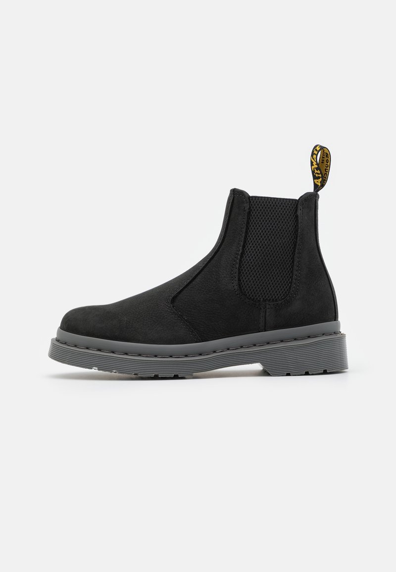 Bottines Chelsea en suède noir avec semelle en caoutchouc gris, panneaux latéraux élastiques et une languette. Présente une finition texturée et des détails de couture minimaux.