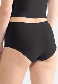 Svarta högmidjade trosor i ett mjukt, lätt material, med en enkel design och sömlösa kanter för komfort.