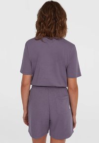 Paarse katoenen T-shirt en bijpassende shorts. Het T-shirt heeft korte mouwen en een ronde hals. De shorts hebben een elastische tailleband en een achterzak.