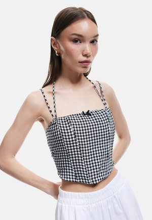 Zwart-witte geruite crop top met dunne, ingevlochten banden, voorzien van een subtiele strikdetail aan de voorkant en een aansluitend lijfje ontwerp.