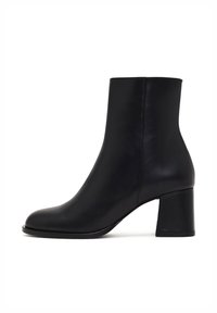 Bottine en cuir noir avec une texture lisse, bout arrondi et un talon bloc épais. Présente un design élégant et minimaliste.