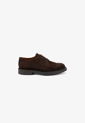 Scarpe lacci in suede marrone scuro con punta rotonda, suola piatta in gomma e dettagli di cucitura minimi sulla tomaia. Rivestimento interno liscio.