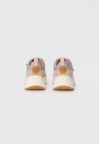 Beige Sportschuhe mit einem Obermaterial aus strukturiertem Stoff, gepolstertem Kragen und einem hexagonalen Logo. Kontrastierender pastellfarbener Fersenbereich und Sohle aus Gummi.