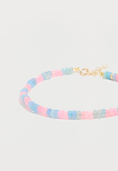 Πλεχτό βραχιόλι με διάφανα ροζ και μπλε στρογγυλά χάντρες και μικρό χρυσό κούμπωμα σε λευκό φόντο.