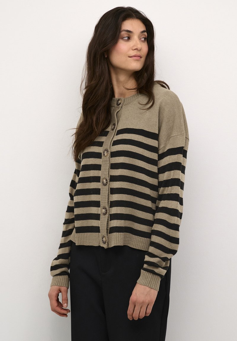 Kootud kardigan pruunis toonis julgete mustade triipudega, ümar kaelus, nööpidega ees ja soonikuäärtega varrukad. Pehme tekstuur ja lühike lõige.