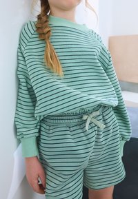 Ensemble de sweat-shirt et de shorts rayé couleur vert clair, en tissu doux ; comprend une taille élastique et un détail de cordon de serrage.