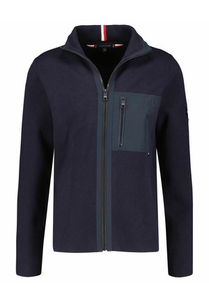 Navy blue full-zip jacket with high collar, chest zip pocket, and subtle red, white, and blue trim inside collar.