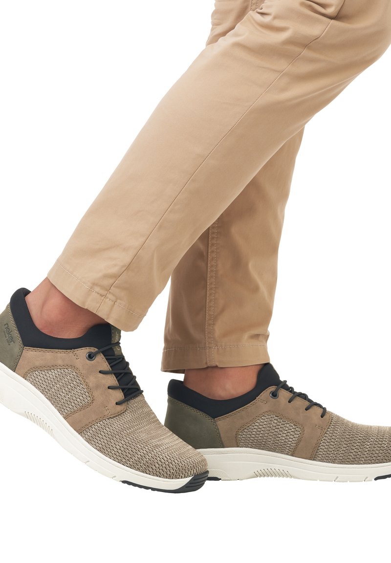 Beige breathable sneakers with a textured mesh upper, dark blue accents, and a white sole. Lightweight design with laces and cushioned heel.