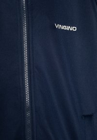 Tamno plava dukserica sa zatvaračem, izrađena od glatkog materijala, sa srebrnim patentnim zatvaračem i izvezenim logom "VINGINO" s lijeve strane.