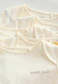 Három krémszínű baba body puha anyagból, különféle finom mintákkal és a "HAPPY DAYS" felirattal dombornyomott betűkkel.