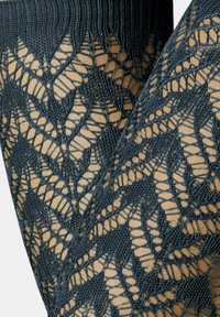 Schwarze Spitzenstrumpfhosen mit Chevron-Muster, einem strukturierten Design und durchsichtigen Abschnitten, die eine Mischung aus komplexen und glatten Elementen zeigen.