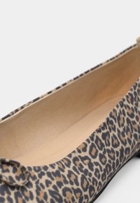 Μπαλαρίνα με λεοπάρ σχέδιο και στρογγυλεμένη μύτη, κατασκευασμένη από απαλό ύφασμα, με μπεζ εσωτερική επένδυση και ένα μικρό φιόγκο στο μπροστινό μέρος.
