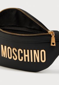 Μαύρο τσαντάκι από ψεύτικο δέρμα με χρυσό φερμουάρ και γράμματα "MOSCHINO". Διαθέτει στρογγυλεμένο σχήμα και λεία υφή, με άνοιγμα με φερμουάρ.