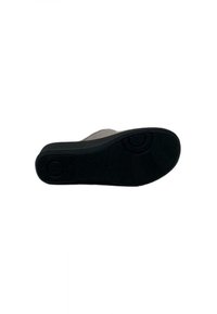 Suola di una scarpa con superficie in gomma nera testurizzata, caratterizzata da motivi circolari e un design piatto. La scarpa ha un bordo superiore di colore chiaro.