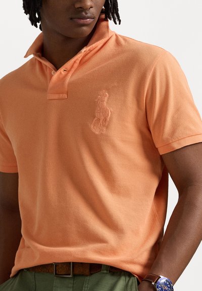 Polo shirt in lichtoranje, gemaakt van katoen met een gestructureerde afwerking. Kenmerkt zich door een opstaande kraag en een geborduurd logo op de borst.