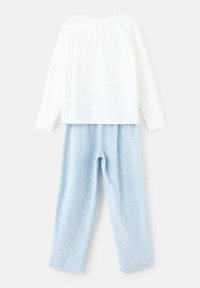 Bijela majica dugih rukava uparena sa svijetloplavim, mekanim pidžama hlačama s malim bijelim točkicama. Opušteni kroj, tekstura slična pamuku.