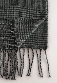 Écharpe à carreaux gris et noir, avec une texture douce et des bords frangés. Le matériau semble tissé avec un design léger et chaud.