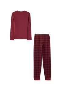 Top de manga larga burdeos y pantalones de pijama a cuadros en rojo y negro. Los pantalones cuentan con una cintura elástica y puños ajustados.