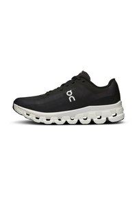 Chaussure de sport noire avec un dessus texturé, semelle intermédiaire blanche dotée d'un design segmenté distinctif, et un logo simple sur le côté.