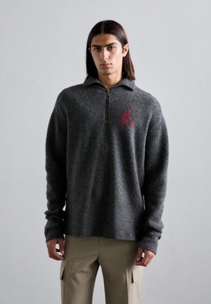 Hallide hallide pullover, mille neljanda lukuga ja soonikkooega kaelusega, millel on rindade kohal punane tikandiga logo ja pikad varrukad.
