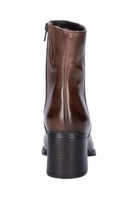 Bottine en cuir marron avec une fermeture éclair sur le côté, bout arrondi et un talon noir robuste. Texture lisse avec des détails de couture subtils.
