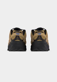 Ζευγάρι ταμπά και μαύρα παπούτσια πεζοπορίας, ορατά από πίσω, με ύφασμα από δίχτυ, παχιά μαύρα πέλματα και λογότυπο "TNF" σε μπλε χρώμα στη φτέρνα.