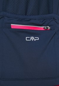Prenda de tela azul marino con diseño de malla, un logotipo prominente de CMP y un bolsillo con cremallera con un acento rosa en el frente.