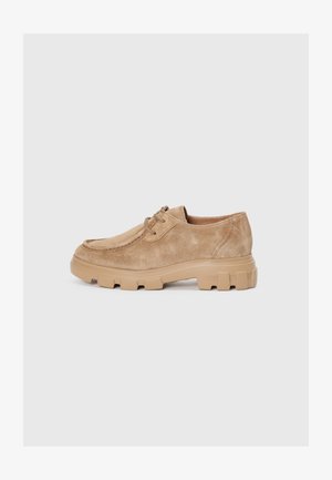 Chaussures en daim beige avec un bout rond et un laçage, dotées d'une semelle en caoutchouc épaisse au détail texturé.